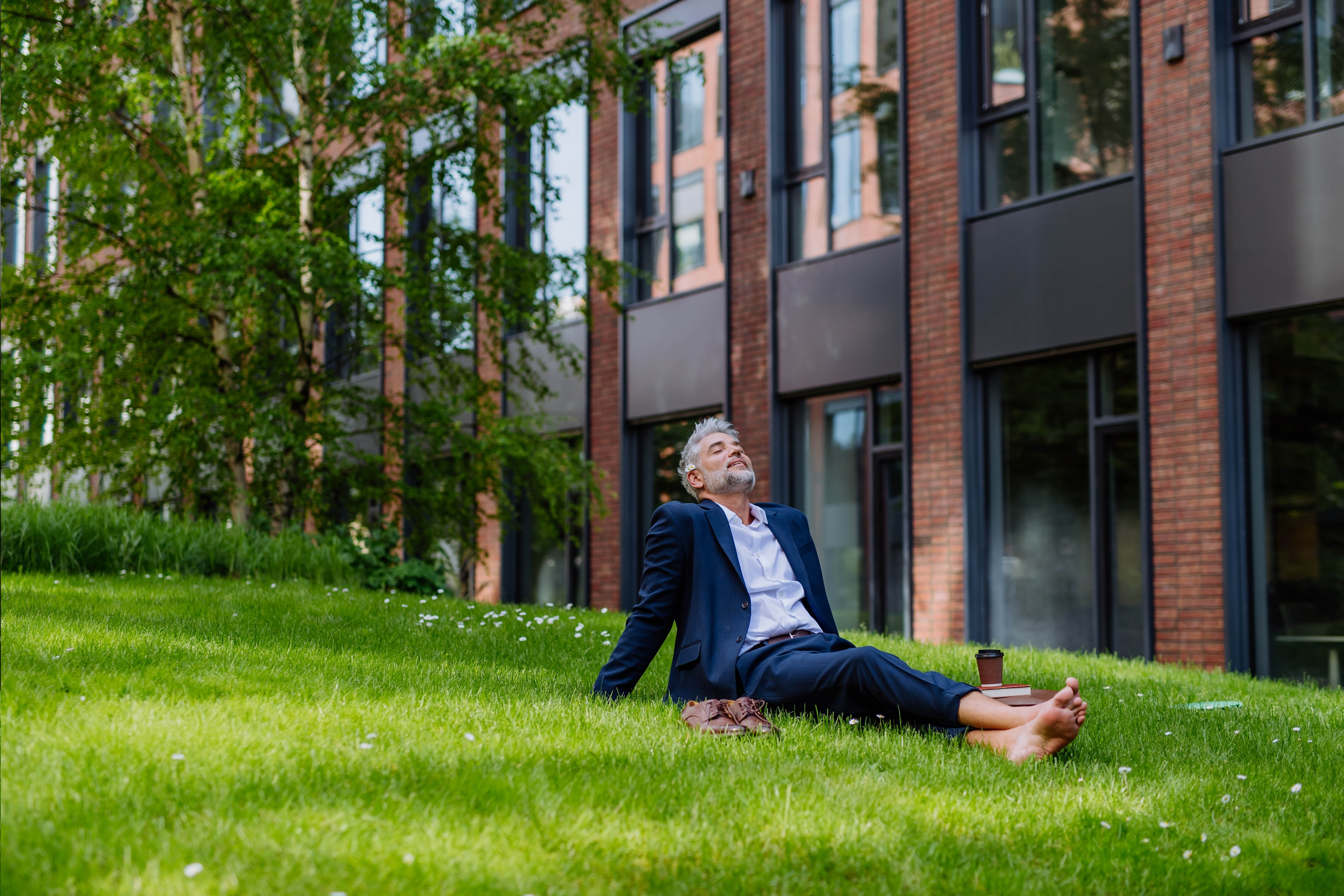 Man sitting on the grass with his bare feet in the city